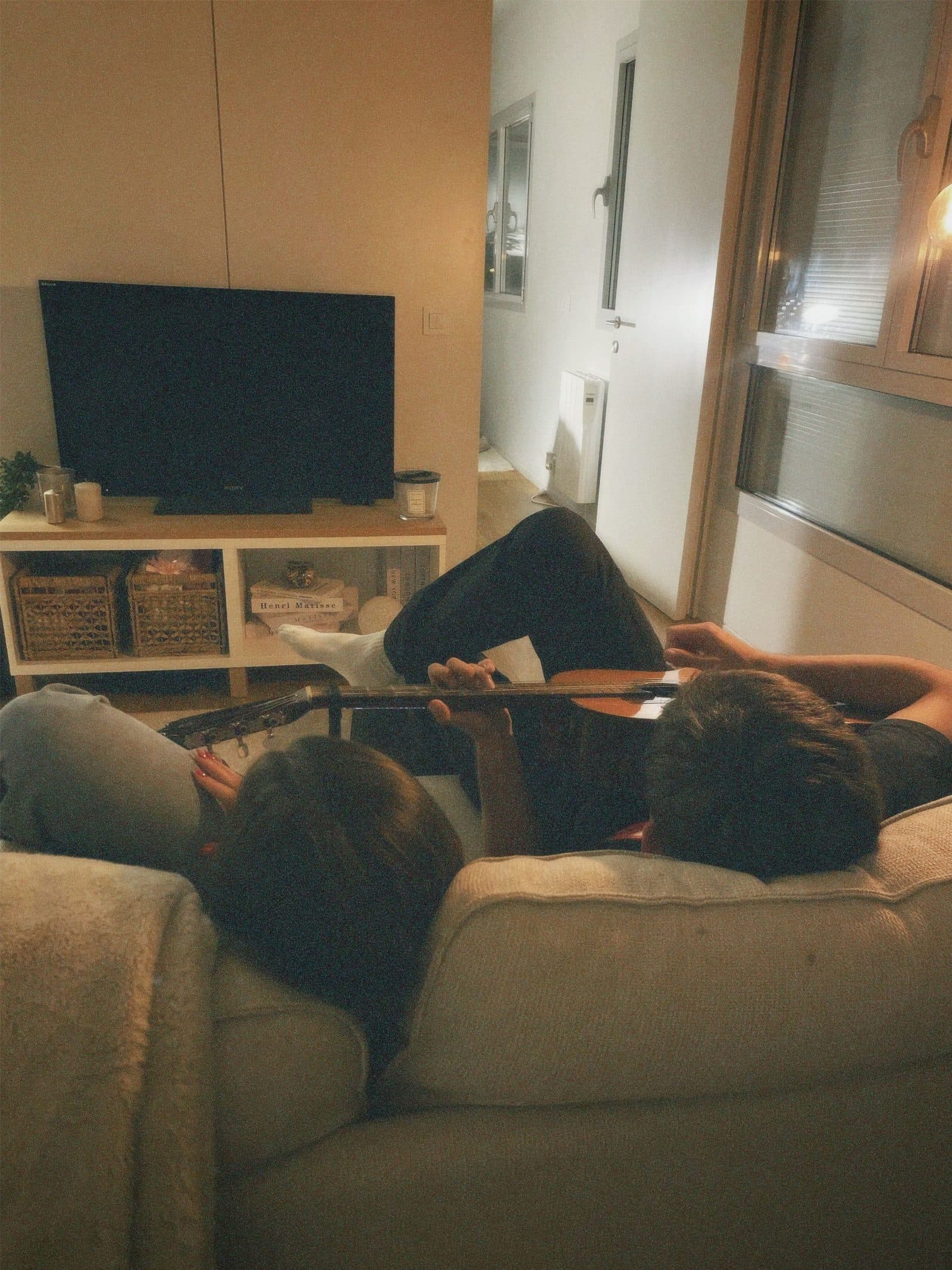 A couple relaxing together on the couch in the evening with a guitar