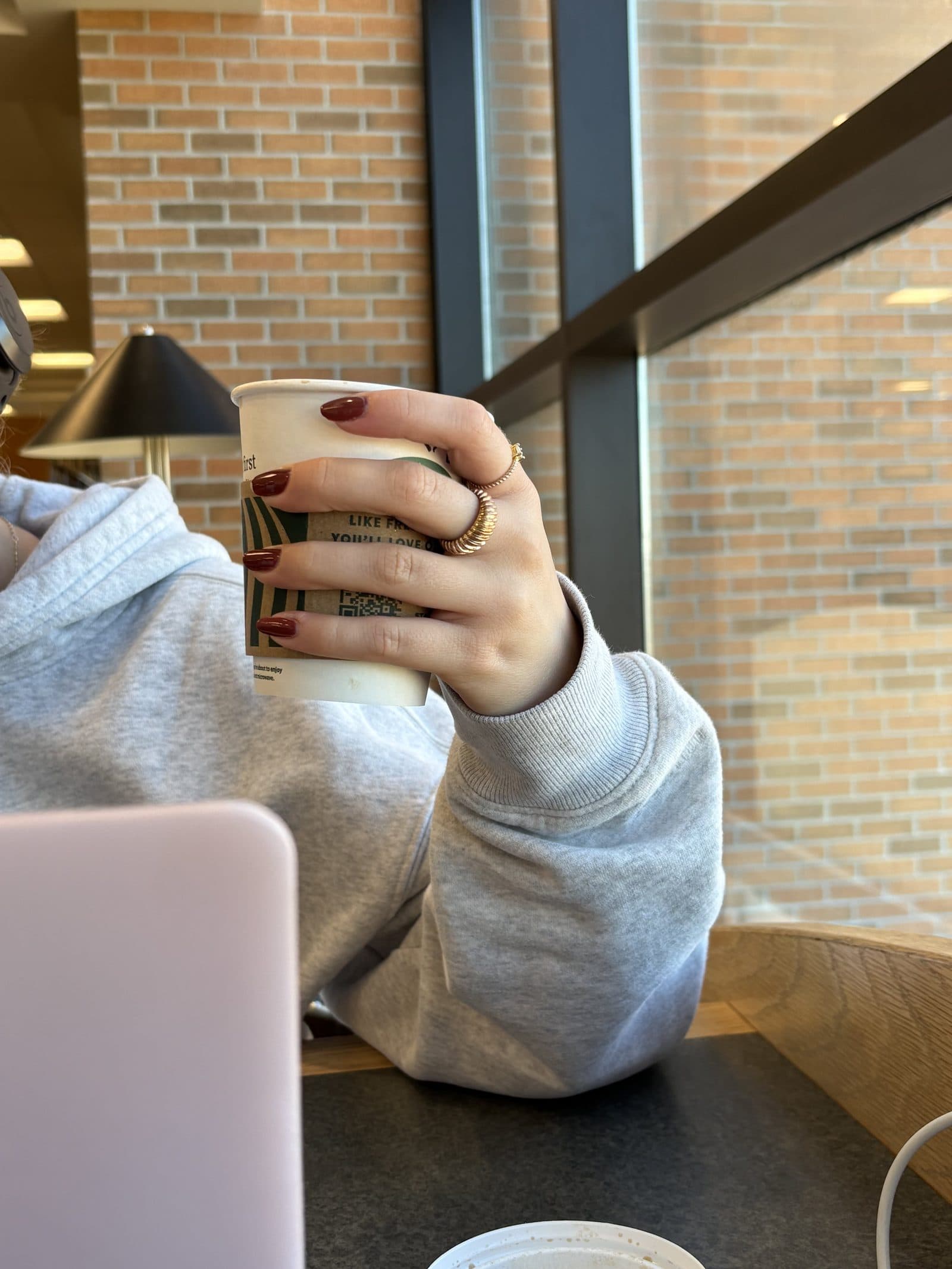 A student with a coffee and laptop at a study spot by the window