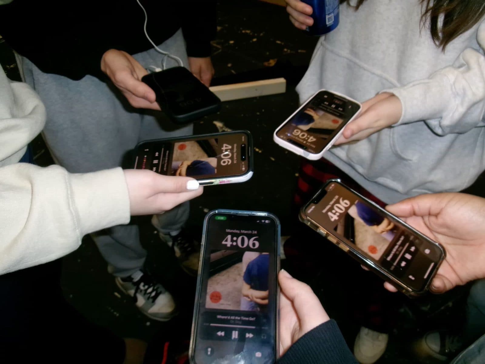 A circle of friends holding up their phones together