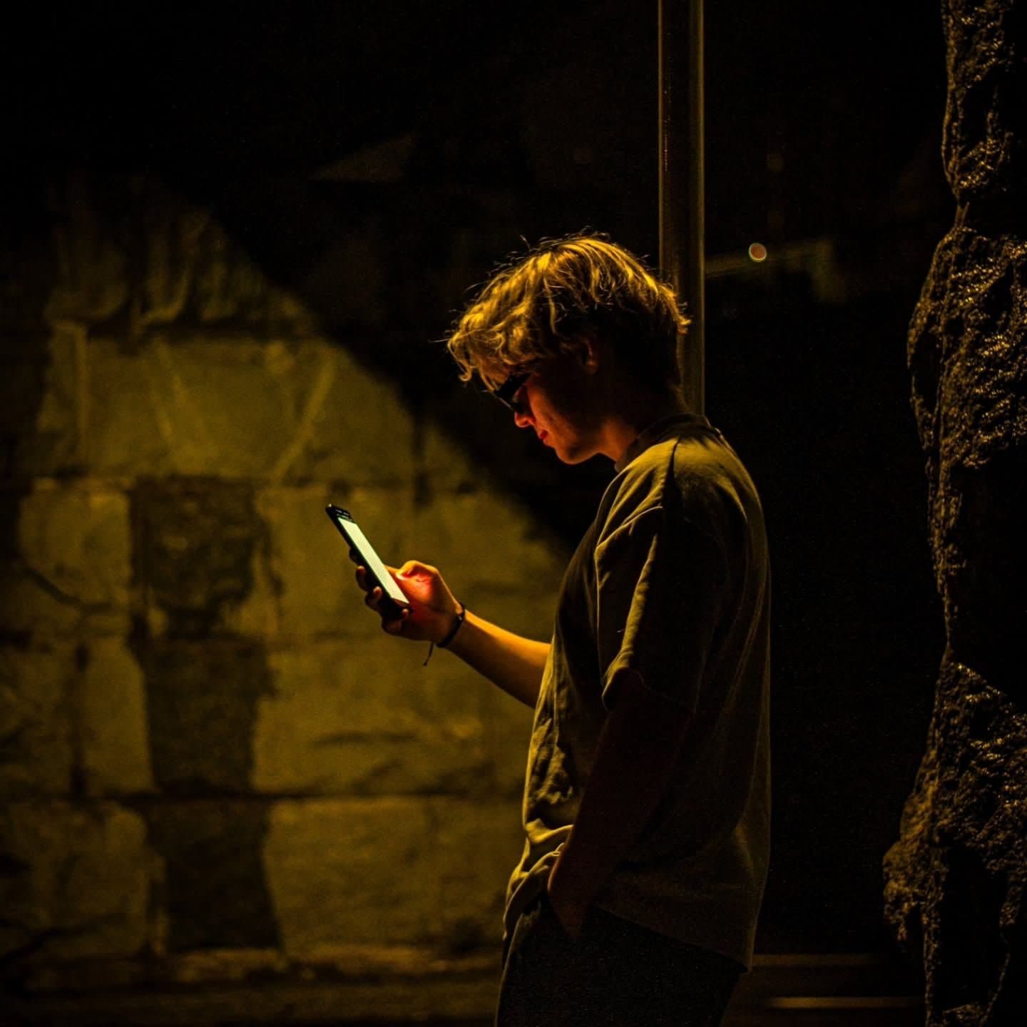 A person lit only by their phone screen at night