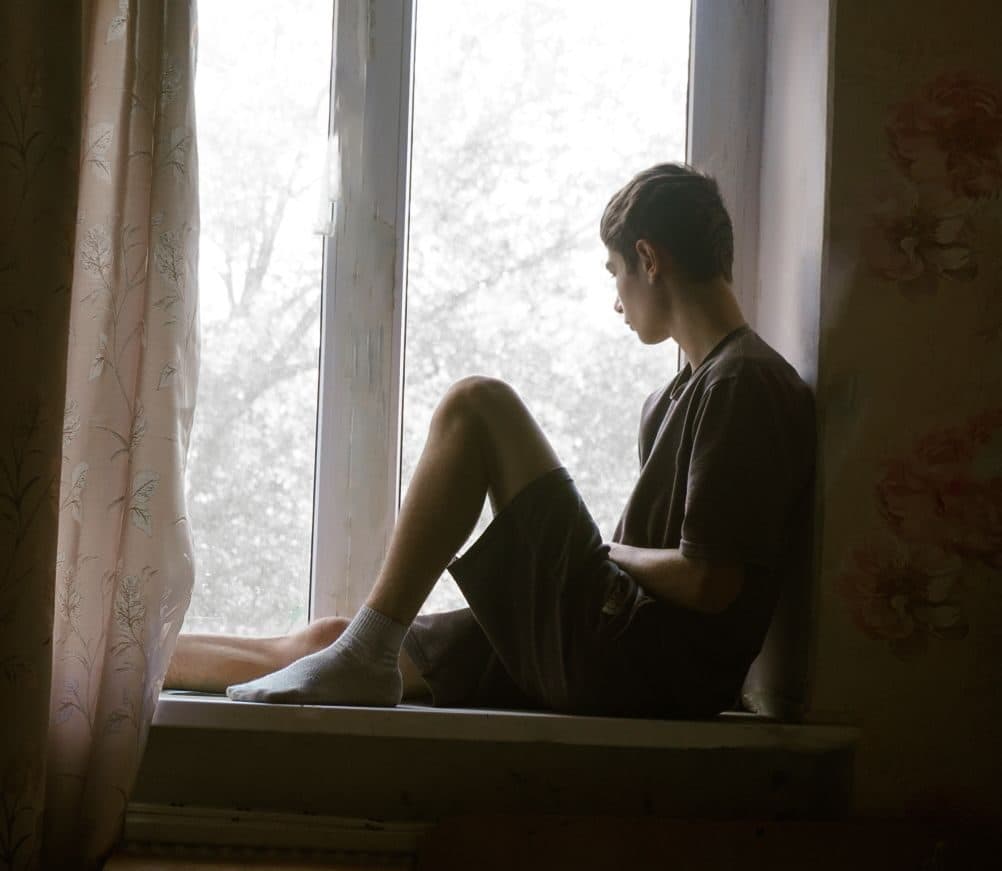 A student sitting in a windowsill looking out, taking a moment