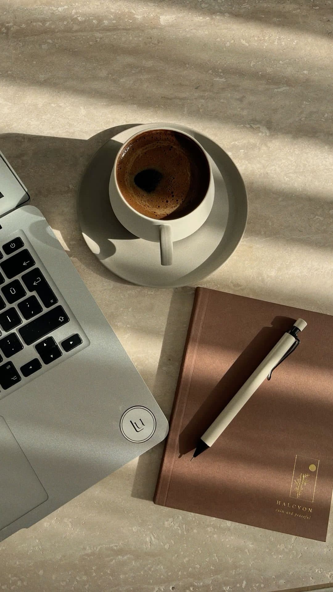 A clean modern workspace with a laptop and notebook in morning light